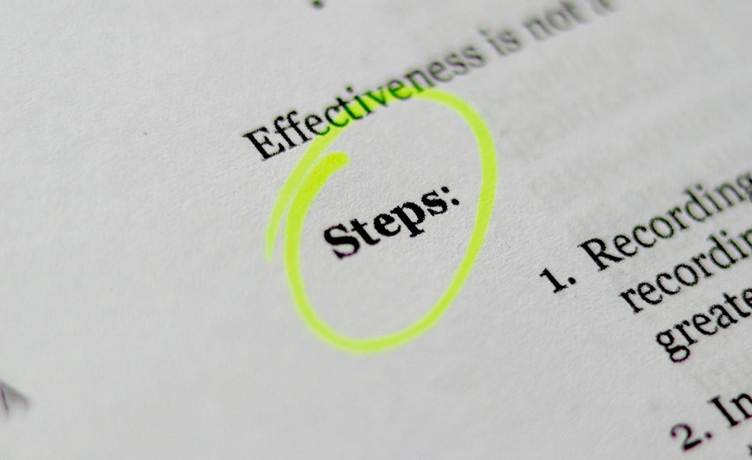 Close-up of a printed document with the word “Steps” highlighted and circled in bright yellow marker, with surrounding text slightly blurred.