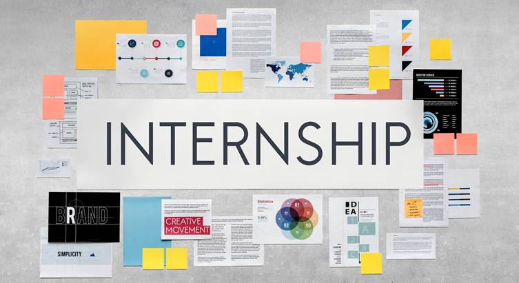 Large white banner with the word “INTERNSHIP” centered on a wall, surrounded by pinned documents, charts, sticky notes, branding materials, and colorful infographic pages arranged in a creative collage layout.